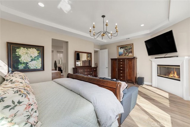 bedroom with a raised ceiling, light wood-type flooring, and a chandelier