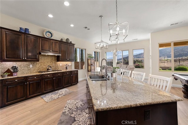 kitchen featuring sink, hanging light fixtures, light hardwood / wood-style flooring, a large island with sink, and a mountain view