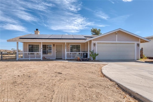 6277 Linda Lee Dr, Yucca Valley, CA 92284 - ranch-style home featuring covered porch, concrete driveway, a garage, solar panels, and a chimney