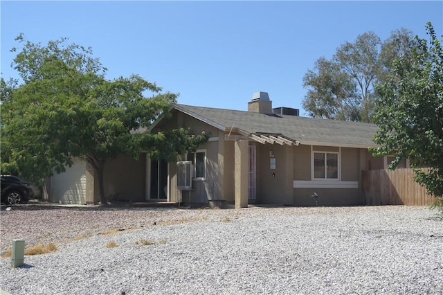 single story home featuring a chimney, fence, and stucco siding