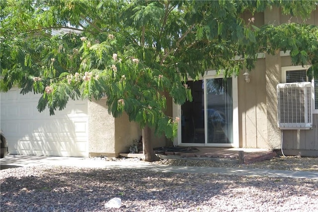 entrance to property with concrete driveway, an attached garage, and stucco siding