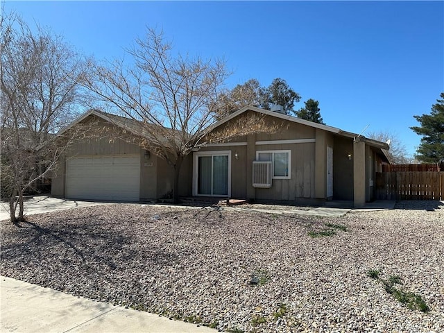 ranch-style house featuring a garage, concrete driveway, and fence