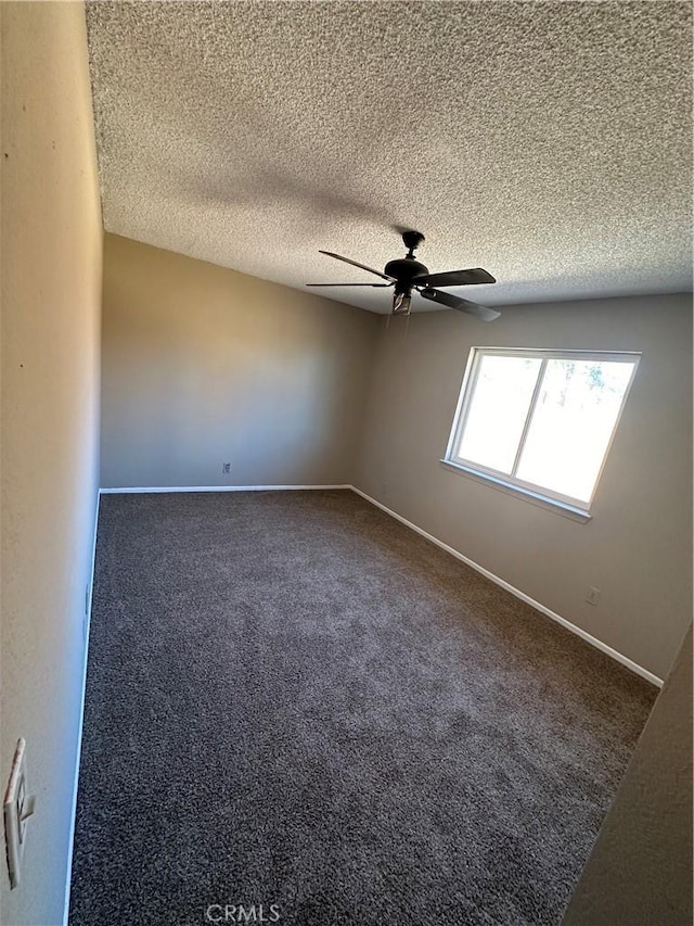 unfurnished room with dark colored carpet, ceiling fan, a textured ceiling, and baseboards