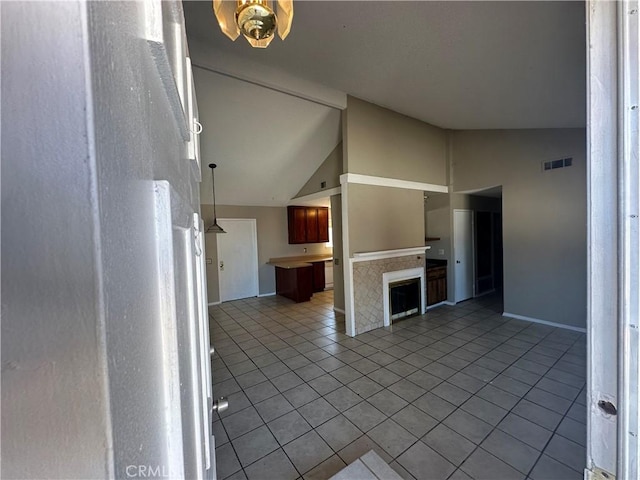 unfurnished living room with light tile patterned floors, baseboards, visible vents, and vaulted ceiling