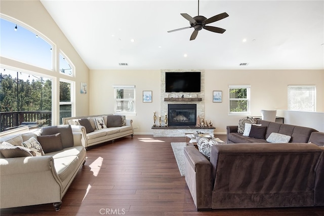 living room featuring a stone fireplace, dark hardwood / wood-style floors, vaulted ceiling, and a wealth of natural light