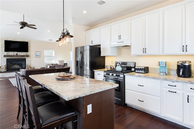 kitchen featuring a kitchen bar, black refrigerator with ice dispenser, stainless steel range with gas stovetop, white cabinetry, and dark hardwood / wood-style floors