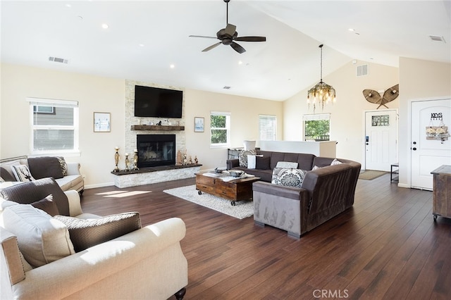 living room featuring high vaulted ceiling, dark wood-type flooring, a fireplace, and ceiling fan with notable chandelier