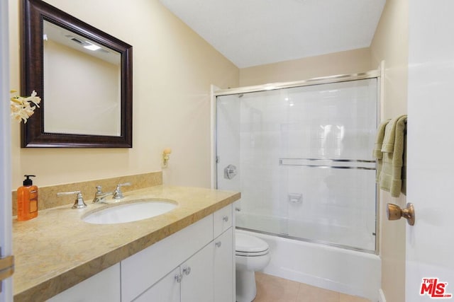 full bathroom featuring shower / bath combination with glass door, vanity, tile patterned flooring, and toilet