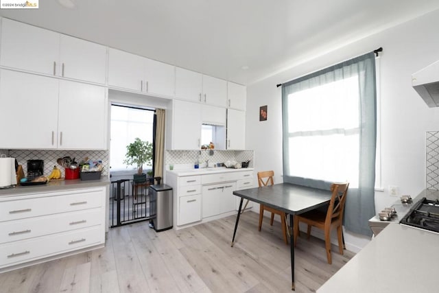 kitchen with white cabinets, light hardwood / wood-style flooring, and tasteful backsplash