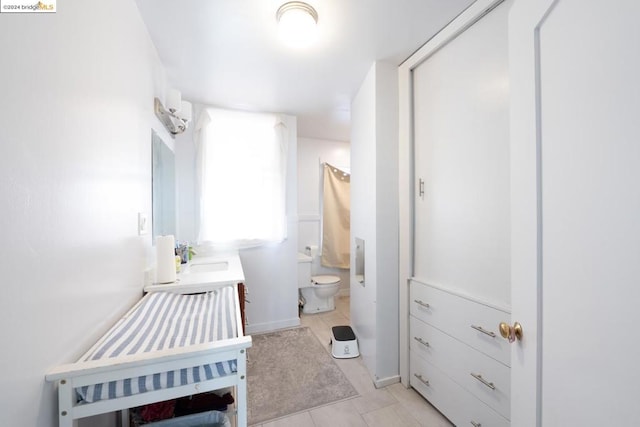 bathroom with toilet, vanity, and tile patterned floors