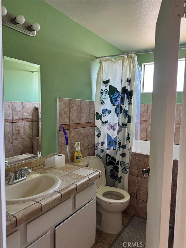 bathroom featuring tile patterned floors, a textured ceiling, vanity, tile walls, and toilet