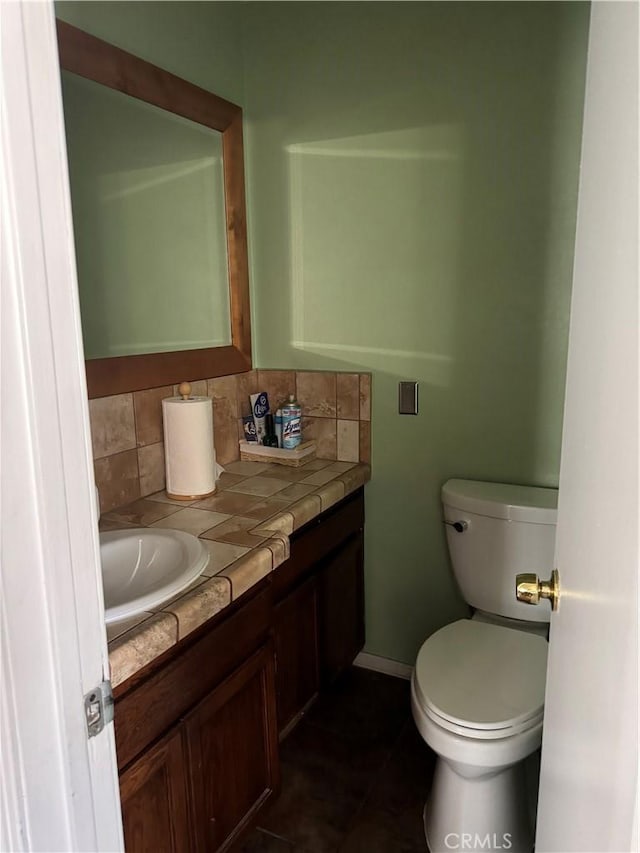 bathroom with tile patterned flooring, vanity, toilet, and tasteful backsplash