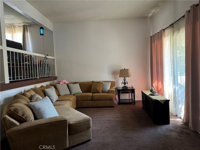 living room with a textured ceiling, dark carpet, and plenty of natural light