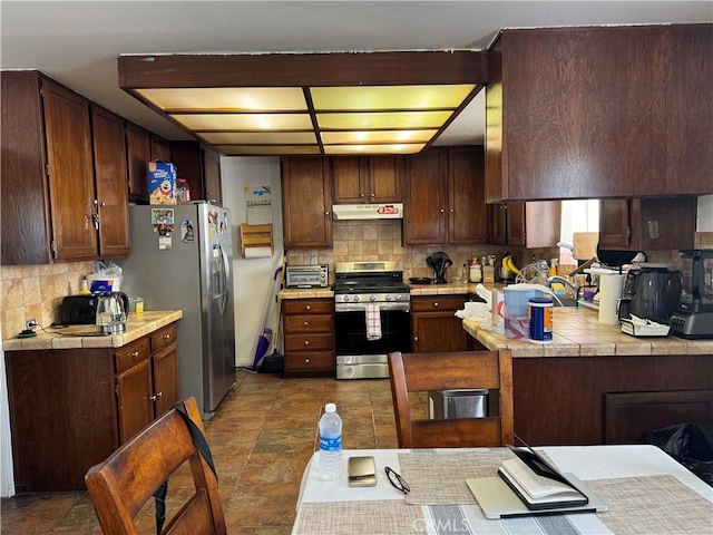 kitchen featuring kitchen peninsula, tasteful backsplash, dark brown cabinetry, stainless steel appliances, and sink