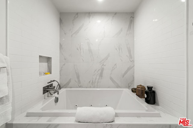 bathroom with tile walls and a relaxing tiled tub