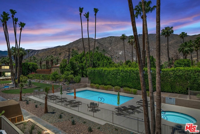 pool at dusk with a mountain view and a patio