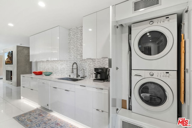 clothes washing area with sink, stacked washer / dryer, and light tile patterned floors