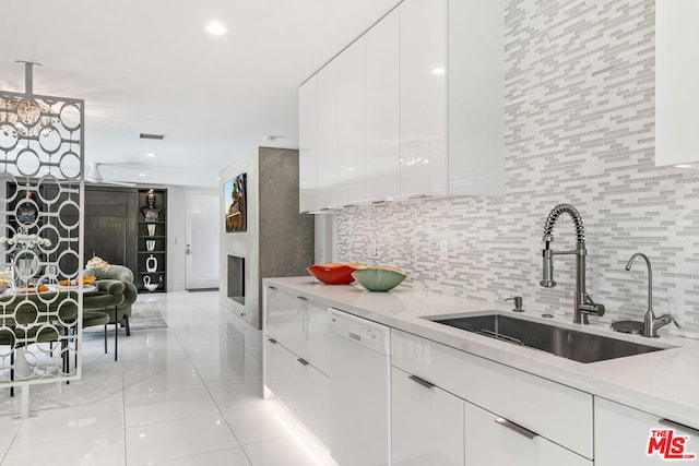 kitchen featuring tasteful backsplash, light stone counters, white cabinetry, white dishwasher, and sink