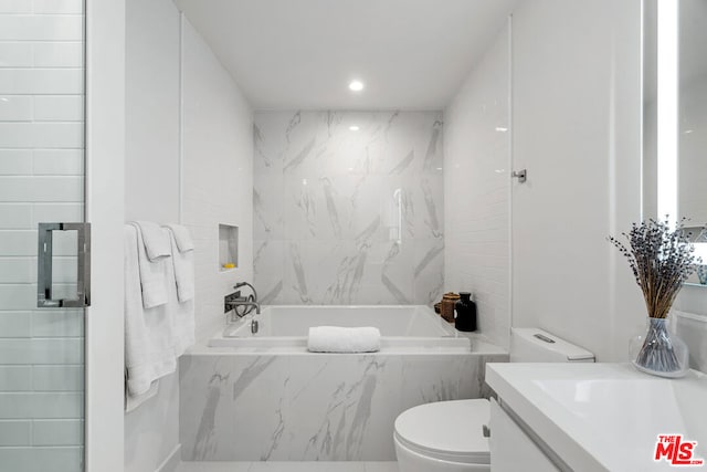 bathroom with vanity, a relaxing tiled tub, and toilet