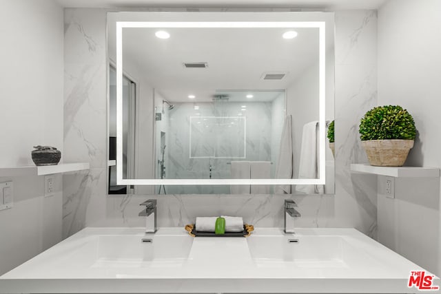 bathroom featuring vanity, a tile shower, and tile walls