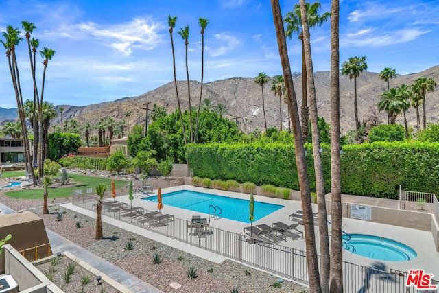 view of pool with a patio, a mountain view, and a hot tub