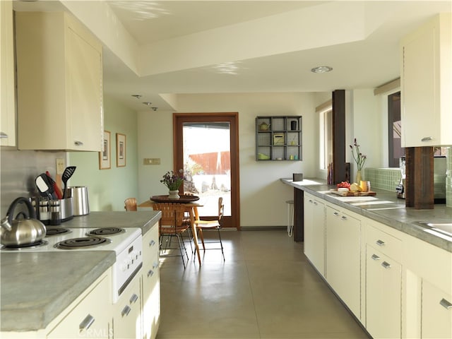 kitchen with white range, white cabinetry, stainless steel counters, and tasteful backsplash