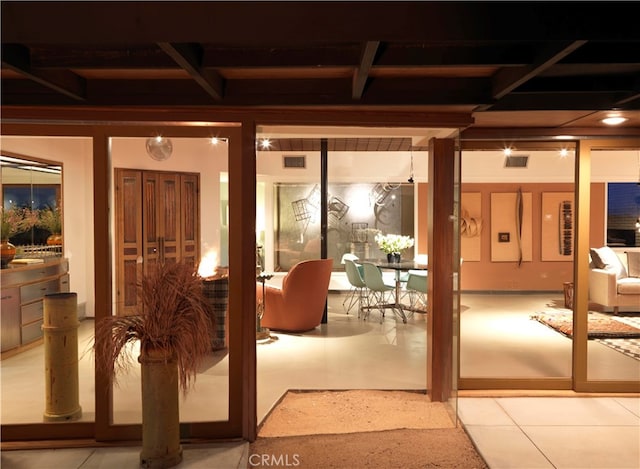 doorway to outside featuring beamed ceiling and tile patterned flooring