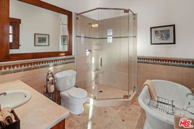 full bathroom with vanity, toilet, tile walls, and separate shower and tub