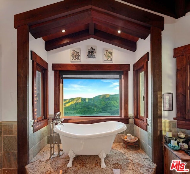 bathroom featuring vaulted ceiling with beams, tile walls, a bathtub, and a mountain view