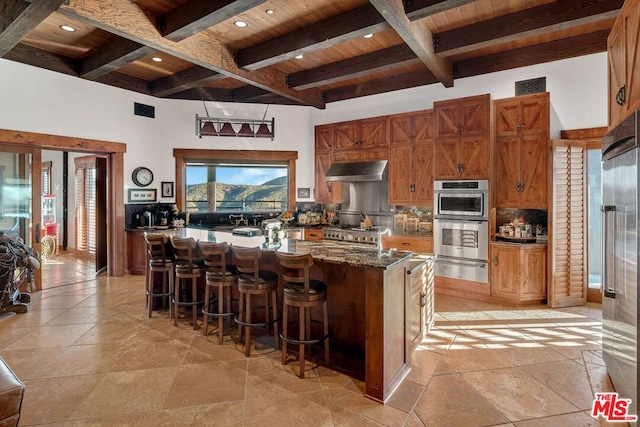 kitchen with beamed ceiling, exhaust hood, wooden ceiling, and a kitchen island