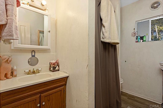 bathroom with vanity, toilet, and hardwood / wood-style floors