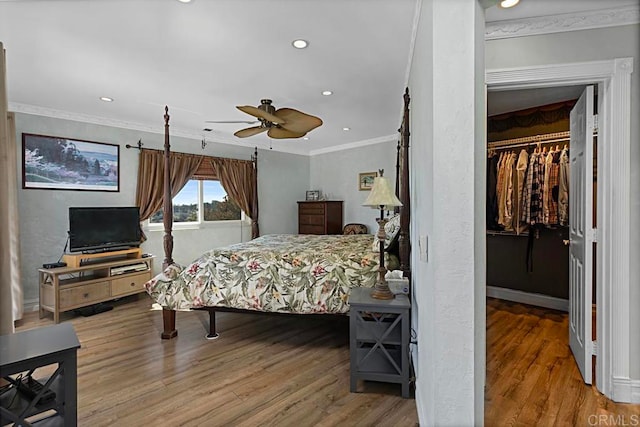 bedroom with wood-type flooring, a spacious closet, a closet, ceiling fan, and ornamental molding