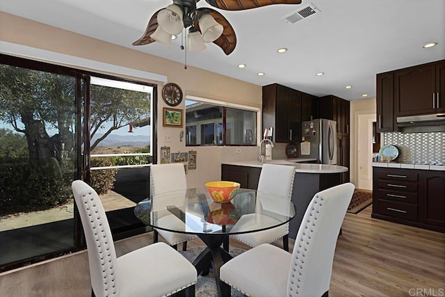 dining space featuring a mountain view, light wood-type flooring, and ceiling fan