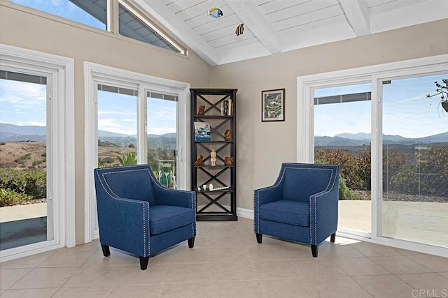 sitting room featuring vaulted ceiling with beams, a mountain view, light tile patterned floors, and plenty of natural light