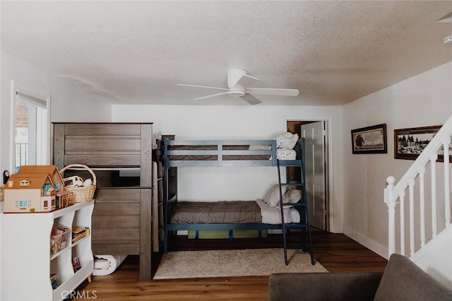 bedroom with a textured ceiling, dark hardwood / wood-style flooring, and ceiling fan