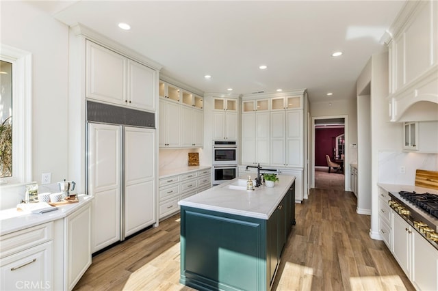 kitchen with appliances with stainless steel finishes, a kitchen island, backsplash, light hardwood / wood-style floors, and white cabinets