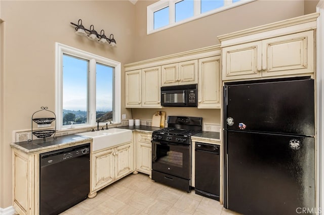 kitchen featuring black appliances, sink, and cream cabinets