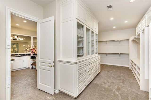 walk in closet with built in desk and light colored carpet