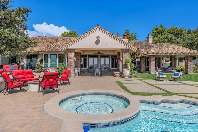 back of property with a swimming pool with hot tub, an outdoor living space, a patio, and ceiling fan