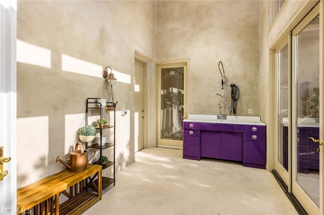 bathroom featuring a towering ceiling, vanity, and concrete floors