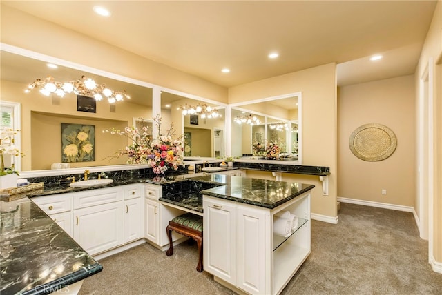 kitchen with white cabinets, light carpet, dark stone countertops, and kitchen peninsula