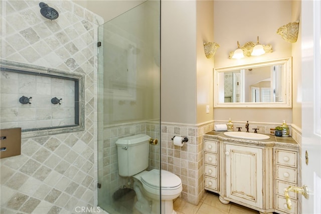 bathroom featuring a tile shower, tile walls, toilet, vanity, and tile patterned floors