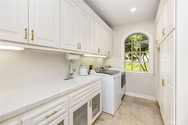 washroom featuring sink, washing machine and dryer, and cabinets