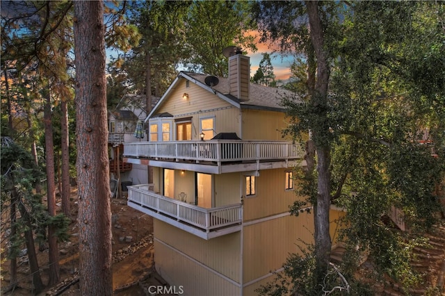 back house at dusk featuring a balcony