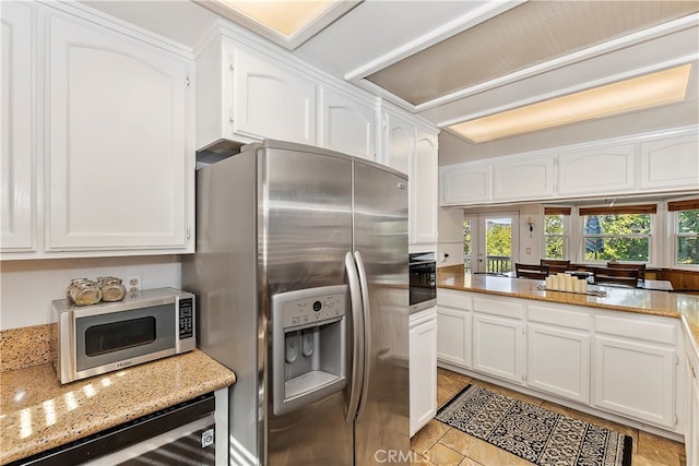 kitchen with white cabinetry, light stone counters, stainless steel appliances, and beverage cooler