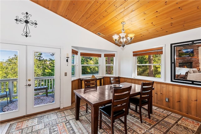 dining space featuring a wealth of natural light, lofted ceiling, french doors, and wood walls