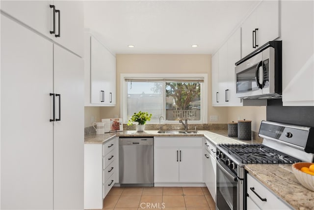 kitchen with appliances with stainless steel finishes, white cabinets, sink, and light tile patterned floors