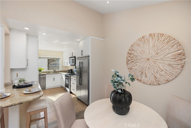 kitchen featuring white cabinets, light stone counters, stainless steel appliances, and light tile patterned flooring