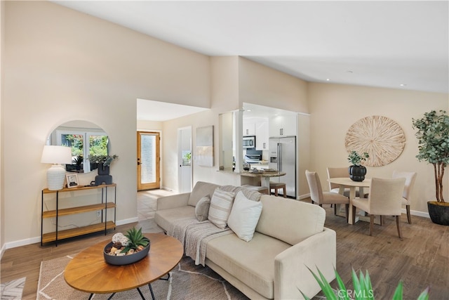 living room with high vaulted ceiling and wood-type flooring