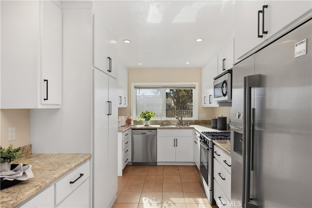 kitchen with white cabinets, light stone counters, light tile patterned flooring, sink, and stainless steel appliances